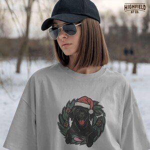 Hand-drawn illustration of black Labrador retriever in Christmas wreath, ideal for dog Christmas shirts or sublimation projects.