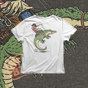 Gator rodeo PNG with cowboy riding alligator in action pose for funny shirt design