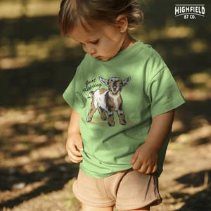 Country goat PNG with an adorable kid goat illustration and the phrase “Just Kidding,” made for funny western farm shirts and goat themed gift items.