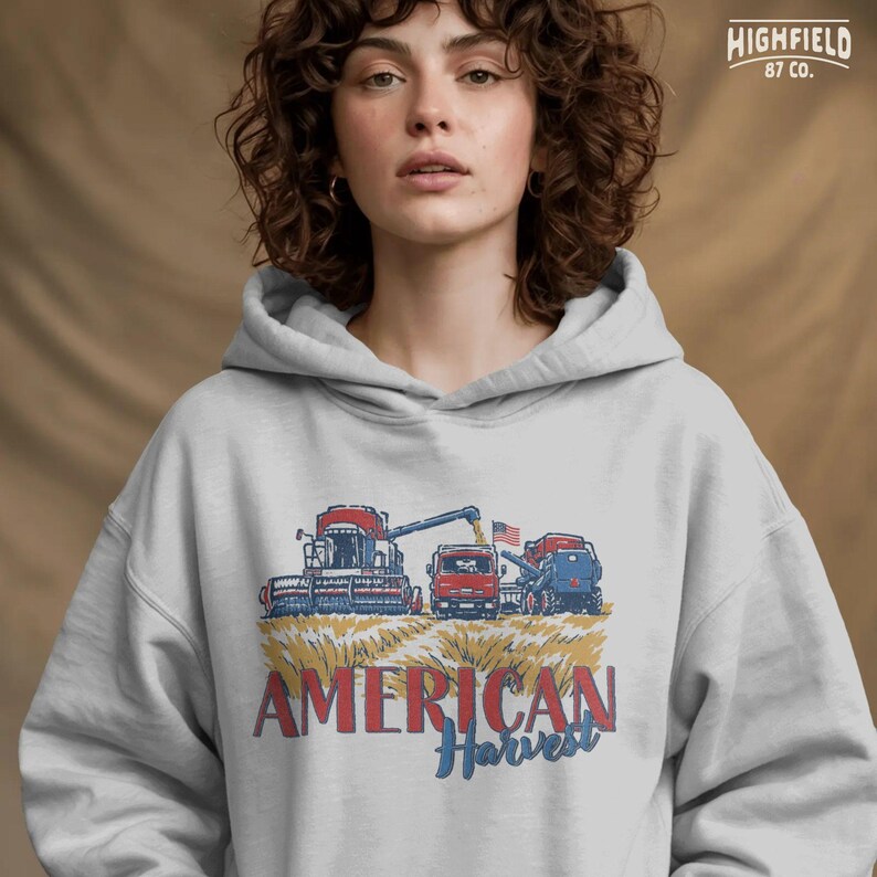 Harvest Season PNG showing farm machines in a wheat field with bold American Harvest text for fall farm shirts and agriculture digital designs.