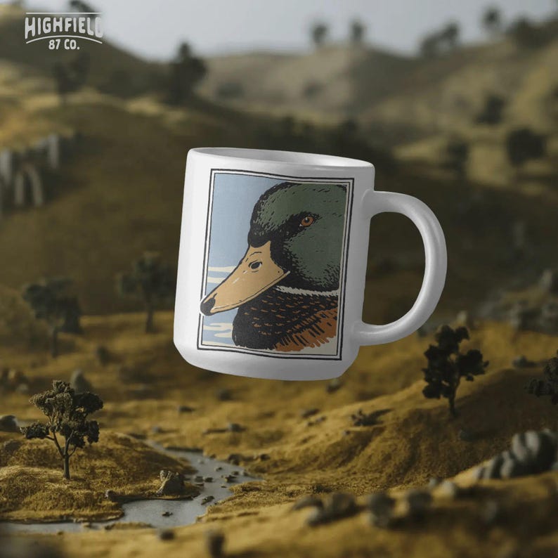 Close up drake duck head illustration with crisp linework, earth tone color palette, and minimalistic background elements. The green head and yellow bill are emphasized in a strong silhouette suitable for waterfowl hunting shirt graphics. Mallard duck PNG digital download created for outdoor apparel and wildlife themed projects.