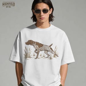 Upland hunting PNG showing a German Shorthaired Pointer pointing in a dry field scene with tall grass and vintage outdoor linework.