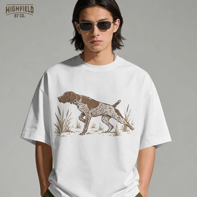 Upland hunting PNG showing a German Shorthaired Pointer pointing in a dry field scene with tall grass and vintage outdoor linework.