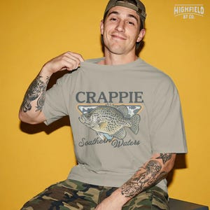 Fisherman PNG design with a crappie fish, southern waters text, and outdoor fishing badge style for summer fishing shirts and digital downloads.