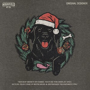 Festive black lab retriever sitting in green Christmas wreath with red baubles, dog bone, and holiday Santa hat. PNG clipart for Labrador Christmas designs.