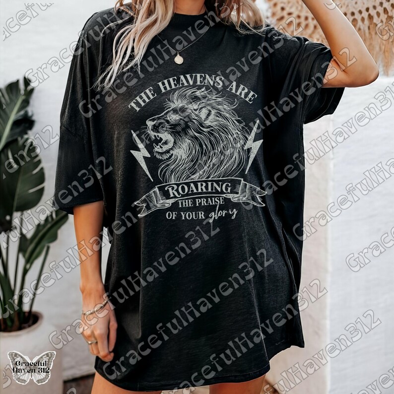 May include: Black oversized t-shirt with a white graphic of a lion roaring with lightning bolts and the text "The Heavens Are Roaring The Praise Of Your Glory".