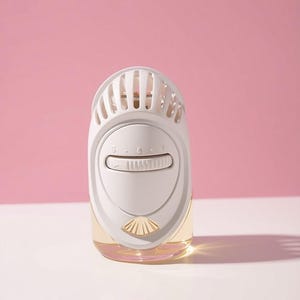 May include: A white plug-in air freshener device with a rounded top featuring vertical vents. The front includes a horizontal adjustment dial labelled with numbers 1, 2, and 3, and a small gold-coloured shell icon at the bottom above a clear glass reservoir.