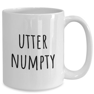 May include: White ceramic coffee mug with black text that reads "UTTER NUMPTY".