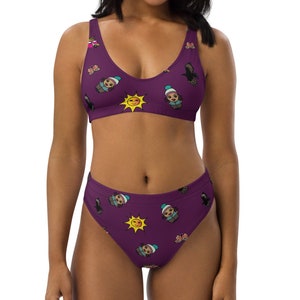 Puede incluir: Bikini de cintura alta de color morado con un patrón repetido de caras de dibujos animados, soles y pájaros. La parte superior del bikini tiene un escote redondo y tirantes ajustables.