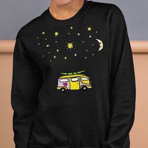 May include: Black sweatshirt with a yellow and pink cartoon van with a surfboard on top. The van has a heart on the side. The van is driving under a night sky with a crescent moon and stars.