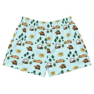 Puede incluir: Shorts deportivos de mujer de color azul claro con un patrón repetitivo de casas, montañas, perros y soles.