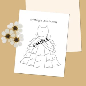 May include: A white sheet of paper with the text "My Weight Loss Journey" and a line drawing of a dress, numbered 1-25. The word "SAMPLE" is printed across the dress. Dried white flowers are in the upper left corner.