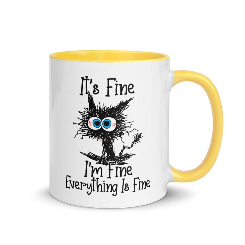 May include: White ceramic mug with a yellow rim and handle. The mug features a black and white cartoon cat with the text "It's Fine I'm Fine Everything Is Fine."