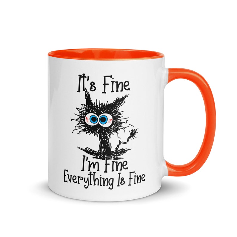 May include: White ceramic mug with an orange rim and handle. The mug features a black and white illustration of a cat with the text "It's Fine I'm Fine Everything Is Fine."