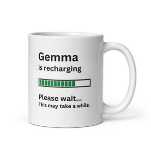 Puede incluir: Taza de cerámica blanca con texto negro que dice "Gemma se está recargando" con una barra de progreso verde y el texto "Por favor, espere... Esto puede tardar un rato."