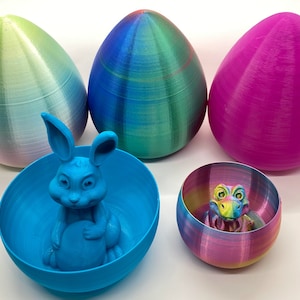 May include: Five 3D printed Easter eggs, one blue, one green, one pink, and two smaller eggs, one blue with a bunny inside and one rainbow with a dinosaur inside.