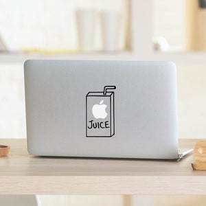 Op de afbeelding: Een zilveren laptop met een zwart-witte sticker van een pak appelsap met een rietje op de dop. De sticker heeft "JUICE" op de voorkant.