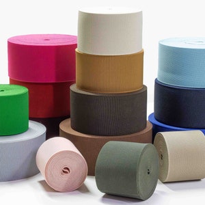 May include: A collection of colorful elastic bands in various colors, including pink, red, green, blue, brown, and beige. The elastic bands are rolled up and stacked on top of each other.
