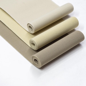 May include: Three rolls of elastic fabric in beige, light brown, and dark brown colours. The fabric is ribbed and has a soft texture.