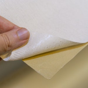K&ouml;nnte beinhalten: Ein wei&szlig;er Canvas-Stoff mit brauner R&uuml;ckseite. Der Stoff wird abgezogen, um die R&uuml;ckseite freizulegen.