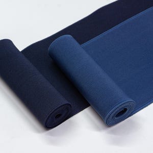 May include: Two rolls of elastic fabric in different shades of blue. The fabric is ribbed and has a soft, stretchy texture.