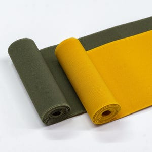 May include: Two rolls of elastic fabric, one in olive green and one in yellow. The fabric is ribbed and has a slight sheen.