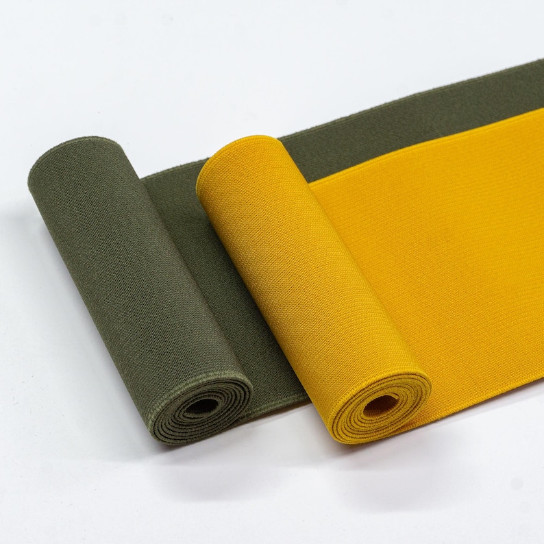 May include: Two rolls of elastic fabric, one in olive green and one in yellow. The fabric is ribbed and has a slight sheen.