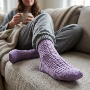 Puede incluir: Un par de calcetines de punto color lavanda con un patrón de tejido de gofre texturizado. Los calcetines están hechos de un hilo suave, llegan hasta la mitad de la pantorrilla y presentan un puño acanalado y talón y puntera reforzados.