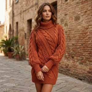 Pode incluir: Um vestido de camisola em malha trançada cor de ferrugem com gola alta, mangas compridas com punhos canelados e um padrão espesso e texturizado de tranças verticais e diagonais em toda a peça, terminando numa bainha canelada acima dos joelhos.