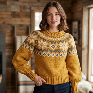 May include: A mustard yellow long-sleeve sweater featuring a crew neckline and a ribbed hem and cuffs. The upper chest and shoulders display a repeating geometric and snowflake pattern in shades of cream and charcoal gray knit into the fabric.