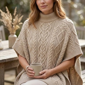 Puede incluir: Un poncho de punto trenzado en color beige con cuello alto y un patrón texturizado de trenzas verticales y formas de diamante. La prenda tiene aberturas anchas para los brazos y un dobladillo acanalado, confeccionada en tejido grueso neutro.