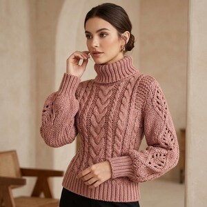 May include: A dusty rose turtleneck jumper featuring a chunky cable knit pattern on the front and intricate openwork leaf-like designs on the sleeves. The garment has long sleeves with ribbed cuffs, a ribbed hem, and a thick, folded turtleneck collar.