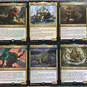 May include: Six Magic: The Gathering trading cards featuring frog-themed legendary creatures. The cards have colorful illustrations and text, with names like "The Gitrog, Ravenous Ride" and "Grolnok, the Omnivore."