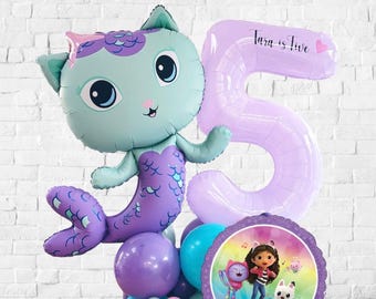 May include: A festive balloon arrangement featuring a mermaid cat character, a large number 5 balloon, and a round Gabby's Dollhouse balloon. The balloons are in shades of blue, purple, and pink, perfect for a birthday celebration.