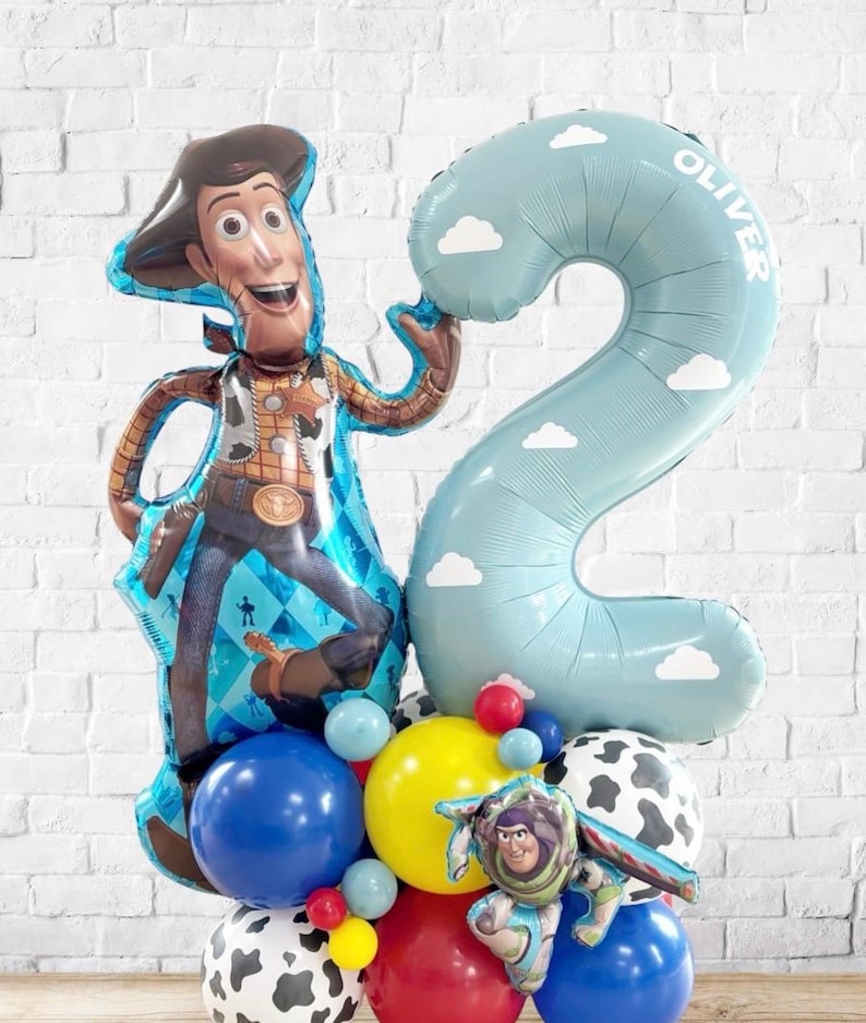 Puede incluir: Un arreglo festivo de globos con un gran globo del personaje Woody y un globo azul claro con el n&uacute;mero 2 y el nombre "Oliver". El arreglo incluye varios globos coloridos, incluyendo globos azules, amarillos, rojos y con estampado de vaca, ideal para una fiesta de cumplea&ntilde;os.
