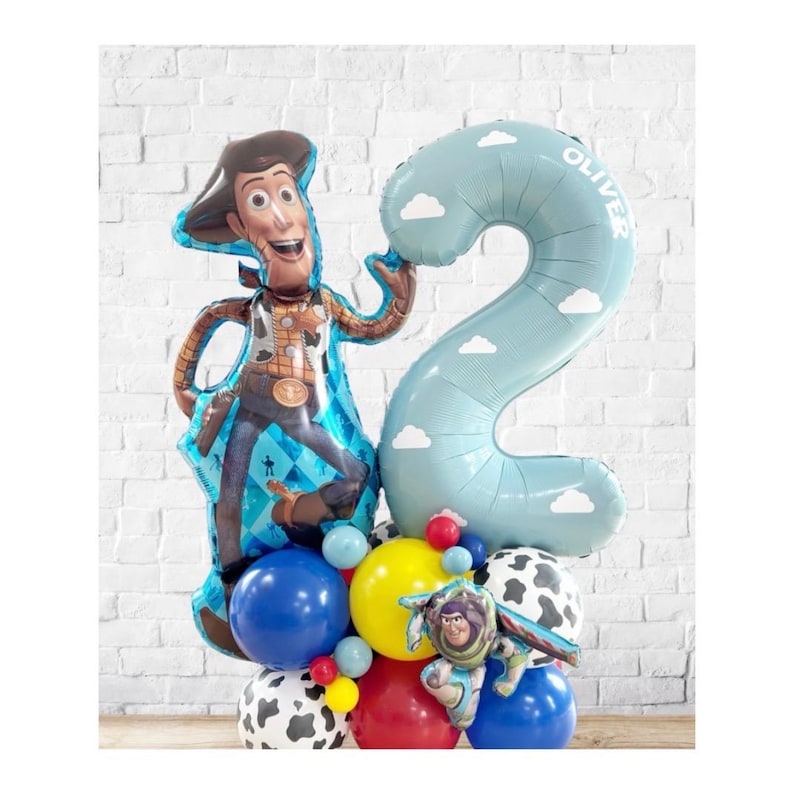 Puede incluir: Un arreglo festivo de globos con un gran globo del personaje Woody y un globo azul claro con el n&uacute;mero 2 y el nombre "Oliver". El arreglo incluye varios globos coloridos, incluyendo globos azules, amarillos, rojos y con estampado de vaca, y un globo de Buzz Lightyear.