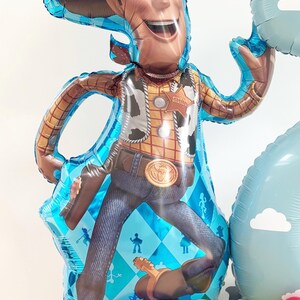 Puede incluir: Un gran globo de Woody de la franquicia Toy Story, con sombrero de vaquero, chaleco y vaqueros. El globo es azul y marr&oacute;n, con otros globos azules, amarillos y rojos en la base. Una divertida decoraci&oacute;n para una fiesta de cumplea&ntilde;os.