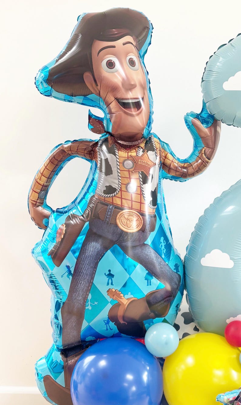 Puede incluir: Un gran globo de Woody de la franquicia Toy Story, con sombrero de vaquero, chaleco y vaqueros. El globo es azul y marr&oacute;n, con otros globos azules, amarillos y rojos en la base. Una divertida decoraci&oacute;n para una fiesta de cumplea&ntilde;os.