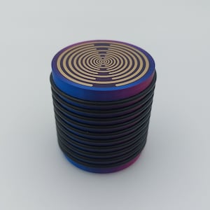 May include: A stack of round, black and blue coasters with a gold concentric circle design on the top coaster.