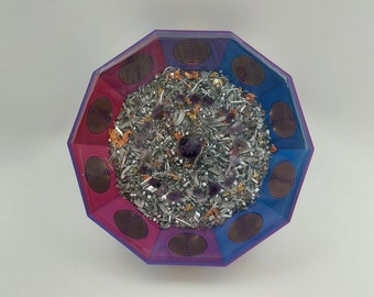Puede incluir: Cuenco octogonal con un diseño de espiral rosa y azul. El cuenco está lleno de virutas de metal plateado, cristales de amatista y escamas de oro.