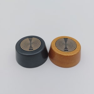 Peut inclure: Deux couvercles ronds, décoratifs, à motifs circulaires. Un couvercle est noir avec un motif doré et l'autre est doré avec un motif noir.