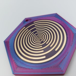May include: A hexagonal, purple and blue, 3D printed coaster with a gold, concentric circle design in the center.