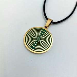 May include: Gold necklace with a round pendant featuring a green spiral pattern.