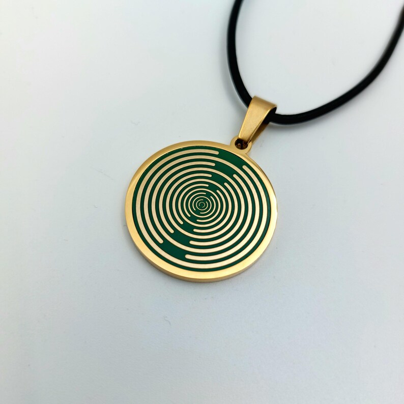 May include: Gold necklace with a round pendant featuring a green spiral pattern.