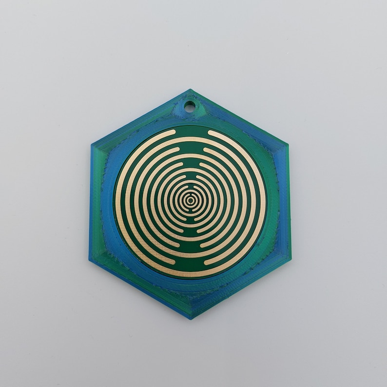 May include: A hexagonal, green and blue, decorative pendant with a gold concentric circle design.