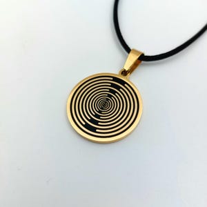 May include: Gold necklace with a round pendant featuring a black and gold spiral design.