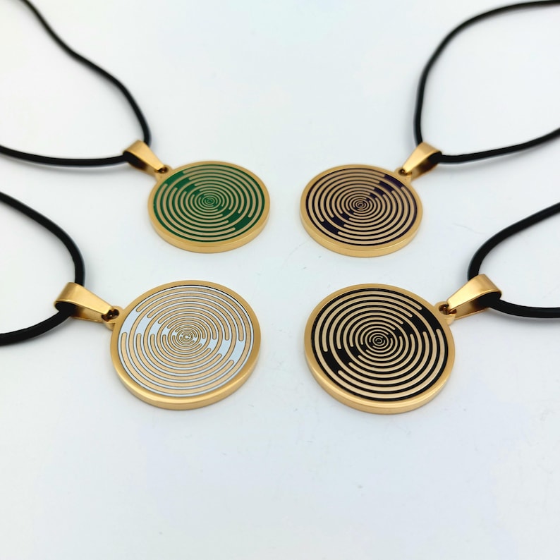 May include: Four gold necklaces with black cords and round pendants featuring a swirling, hypnotic pattern. The pendants are in green, purple, white, and black.