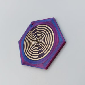 May include: A hexagonal pendant with a concentric circle design in gold on a purple and blue background.