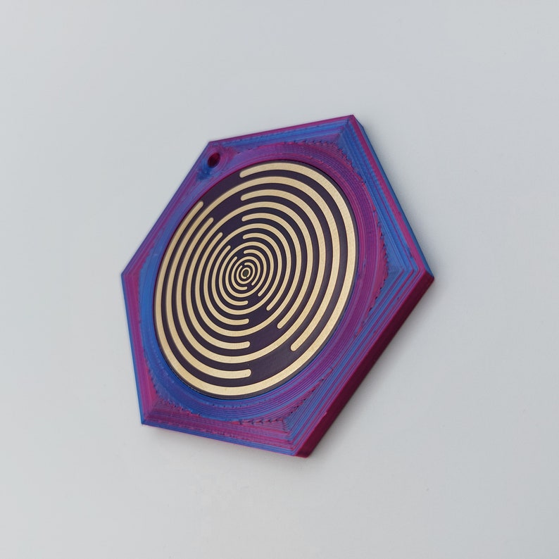 May include: A hexagonal pendant with a concentric circle design in gold on a purple and blue background.