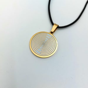 May include: A gold necklace with a round pendant featuring a white and gold concentric circle design.
